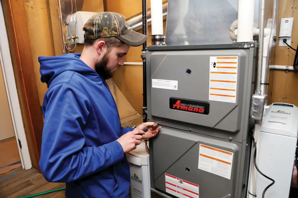 Professional HVAC technician fastening furnace cover during heating system repair.